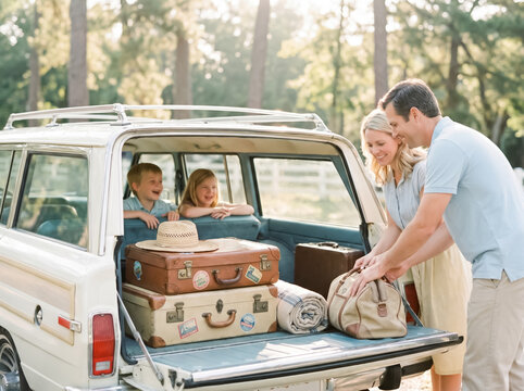 Parents packing vintage luggage into their classic station wagon