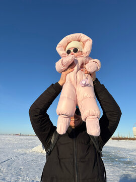 A child in winter clothes in his father's arms.