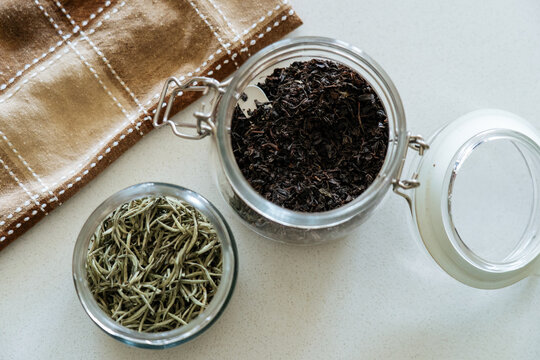 Glass jars with green and black tea leaves 