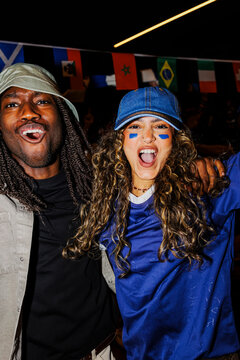 Sports enthusiasts cheering in pub with flags