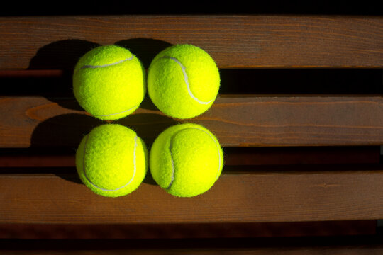 Tennis balls on the bench on a tennis court.