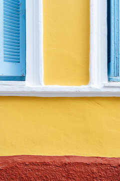 Yellow wall with blue shutters and red base 