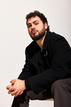 Man sitting with hands clasped in studio setting