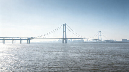 Obraz premium Suspension Bridge Spanning Waterway with City Skyline