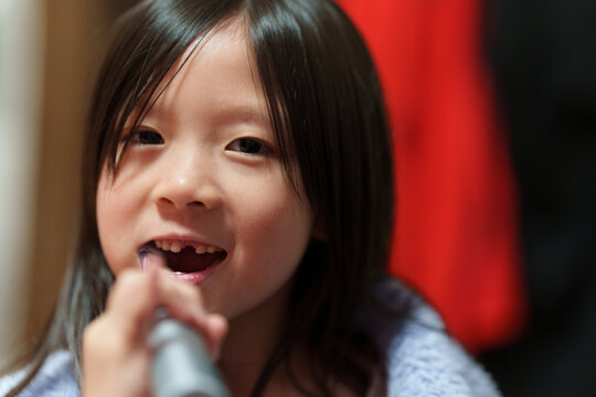 Young Girl Brushing Teeth with Electric Toothbrush