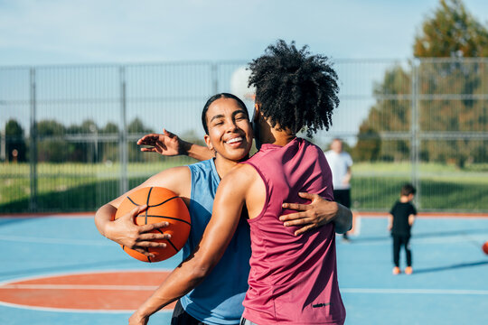 Friends celebrating victory on outdoor basketball court