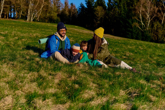 Happy family relaxing together on grassy hillside