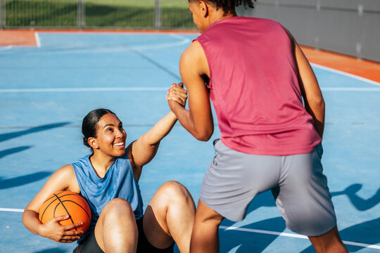 Basketball players helping each other on court