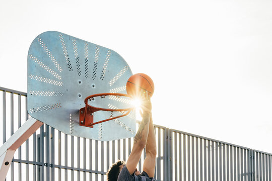 Basketball player scoring with sun shining through hoop