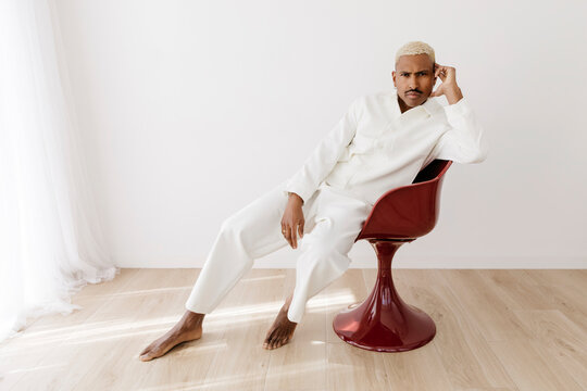 Man in white suit sitting on red chair
