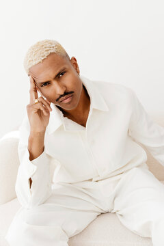 Man with mustache posing on white sofa