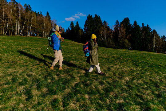 Couple with son hiking across green hillside with backpacks
