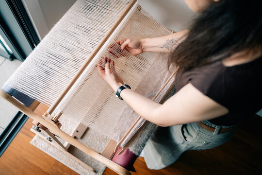 Weaving on a Loom in a Bright Room During the Day