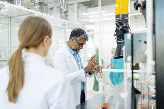 Two scientists young woman and Indian man in real laboratory