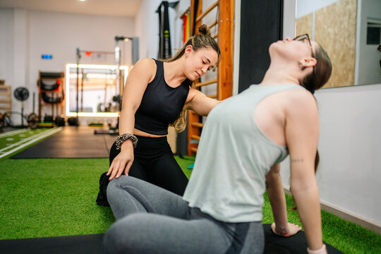 Personal trainer assisting woman during functional training session