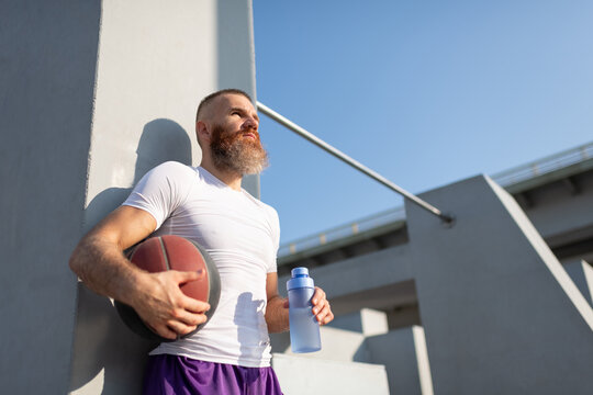 Bearded sportsman with basketball ball and water