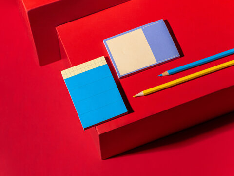Vibrant red background with blue and yellow stationery and pencils