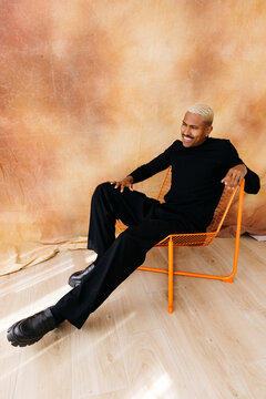 Smiling man sitting on orange chair