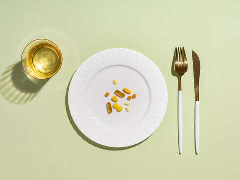 Vitamins and supplements served on a plate with a glass of water