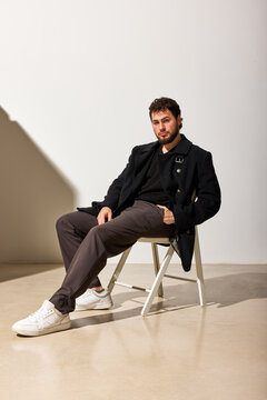 Man sitting on chair in studio with light and shadows