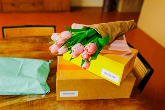 Pink tulip bouquet and parcels on wooden table ugc