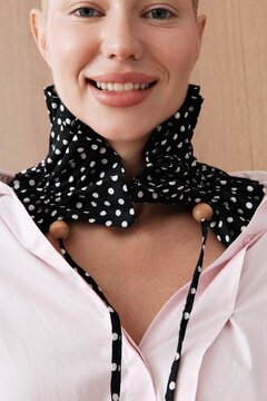Smiling woman in pink shirt and polka dot scarf fashion detail