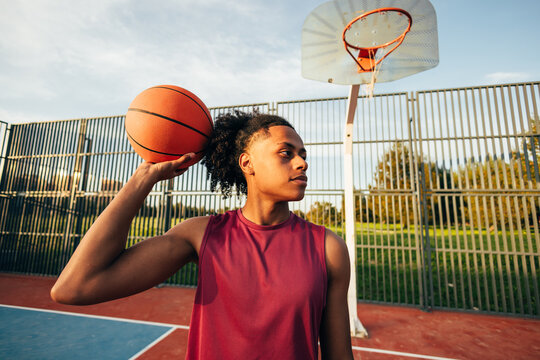 Young athlete holding basketball on outdoor court