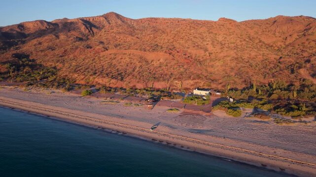 Aerial views show a teardrop camper on the beach in Santa Ines Mulege Baja California Sur Mexico at sunrise near the Sea of Cortez.