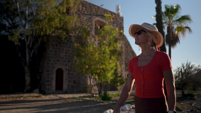 Mature woman discovers the Mission church in Santa Rosalia Mulege Baja California surrounded by oasis palm trees and mountains.