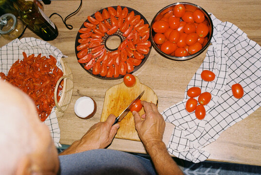 Senior man cutting tomatoes for drying. Preparing sun-dried tomatoes.