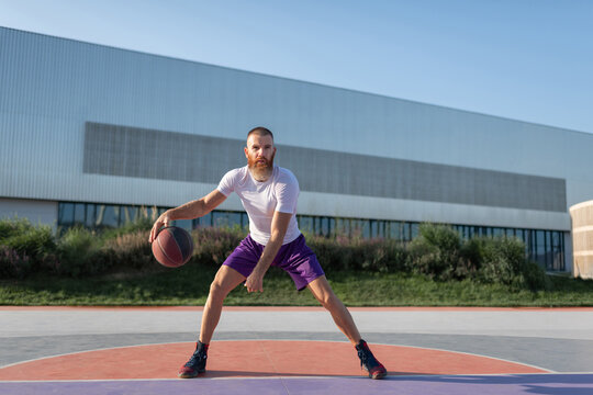 Determined male athlete playing streetball on court
