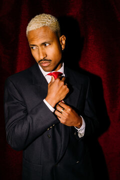 Elegant man adjusting red tie 