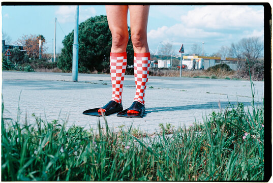 a man in checkered socks and fins stands outside, 35mm film