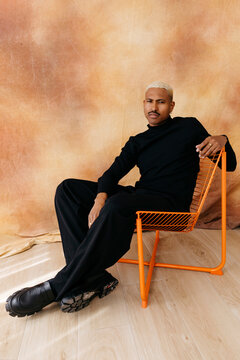 Man sitting orange chair looking confident