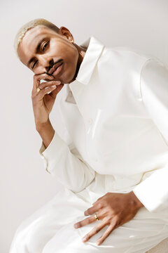 Man wearing white outfit posing thoughtfully