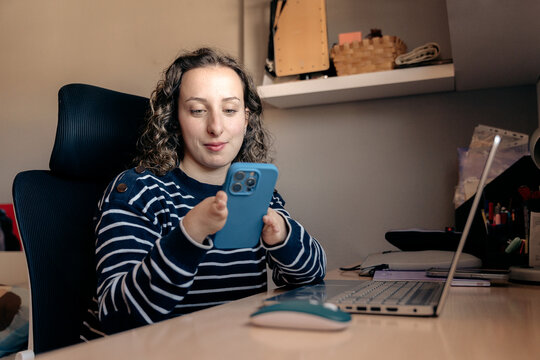 Woman with phocomelia using smartphone at desk