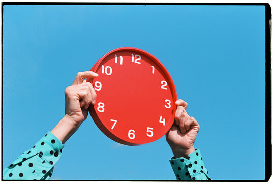 a man raises a red clock with no hands, 35mm film