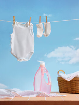 Baby clothes and socks drying on a line with laundry detergent