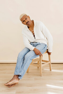 Man posing while sitting on stool