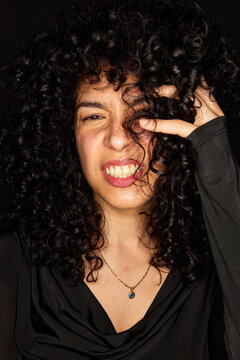 Woman with curly hair expressing emotions in studio setting