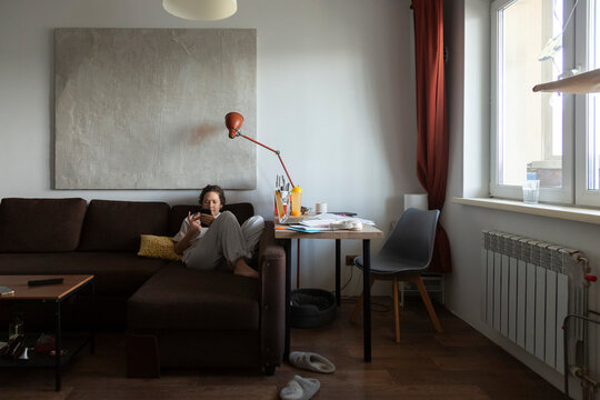 Person relaxing on sofa using smartphone at home
