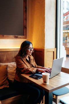 Woman working on laptop in cafe remote workspace