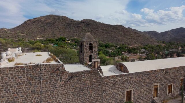 Aerial views show the Mission of Santa Rosalia of Mulege surrounded by desert and mountains in Baja California Sur, Mexico, during late afternoon.