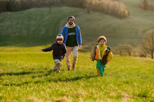 Father and kids running in sunny meadow