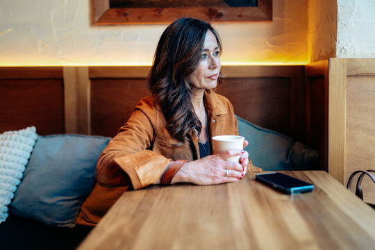 Woman contemplating while drinking coffee in cafe
