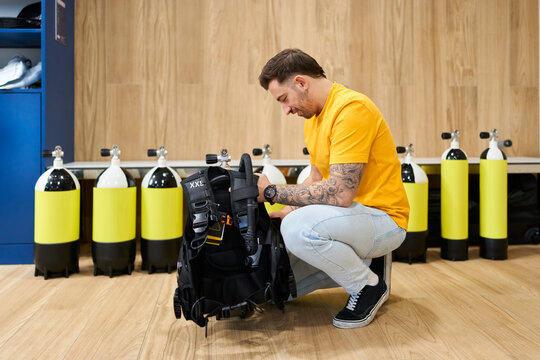 Man preparing scuba diving equipment at dive center