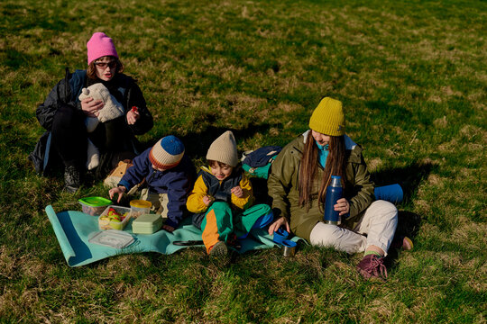 Family picnic during hiking trip on grassy hill