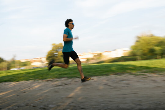 Low angle view of young man running outdoors against blue sky
