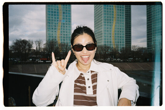 Portrait of Young Woman in Sunglasses Showing Rock Gesture