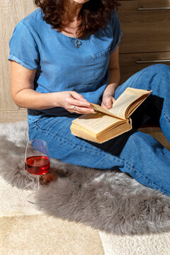 Woman reading book sitting on a sheepskin rug